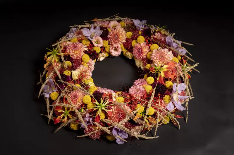 Trauerkranz mit Craspedia, Gloriosa, Jatropha, Clematis, Achillea und Scabiosa