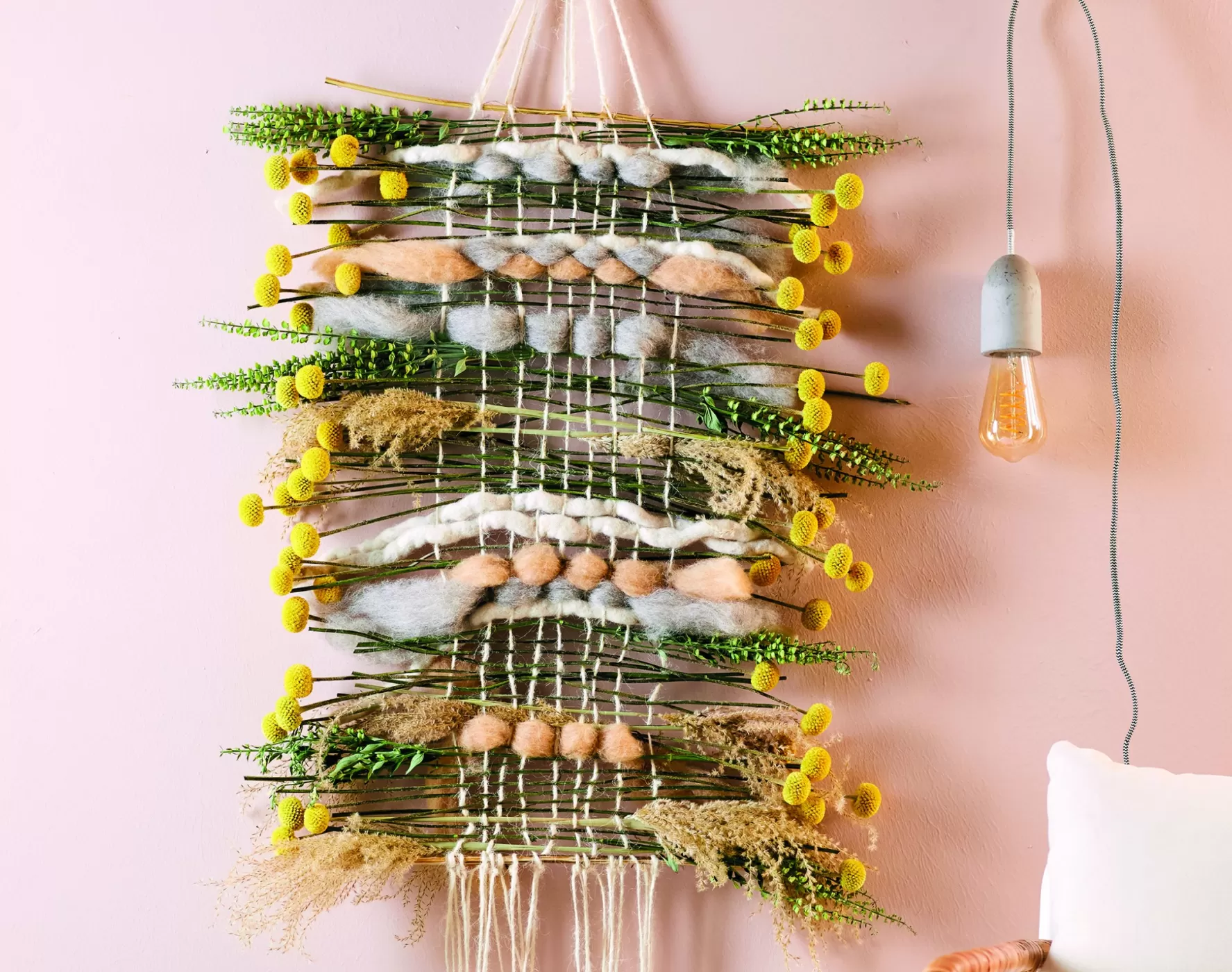 weaving frame filled with Craspedia, Miscanthus, Scutellaria, twigs and wool woven in between the strings